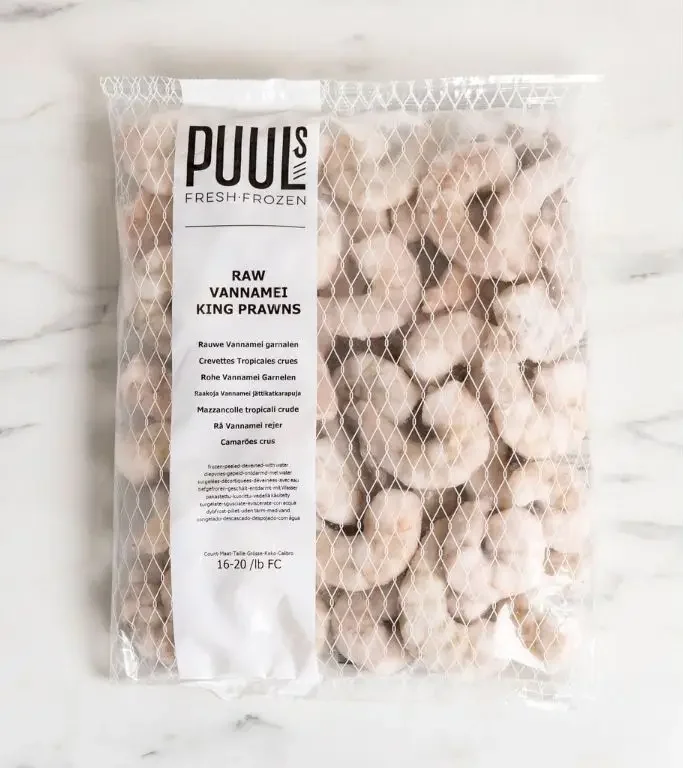 Poki af frosnum rækjum á marmaraborði